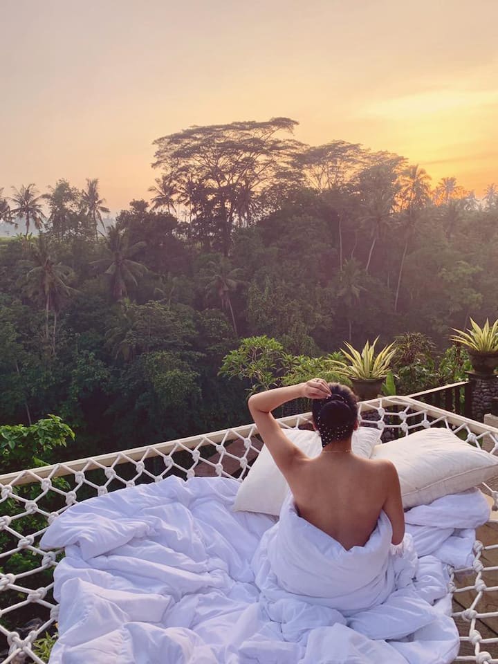 Girl in sky bed overlooking the Balinese jungle in Villa Cella Bella, a Bali luxury Airbnb