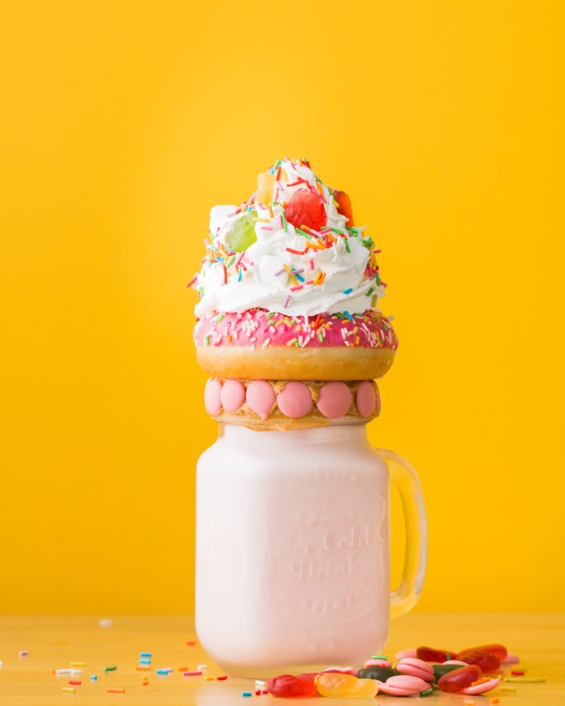 A pink freak shake topped with a doughnut