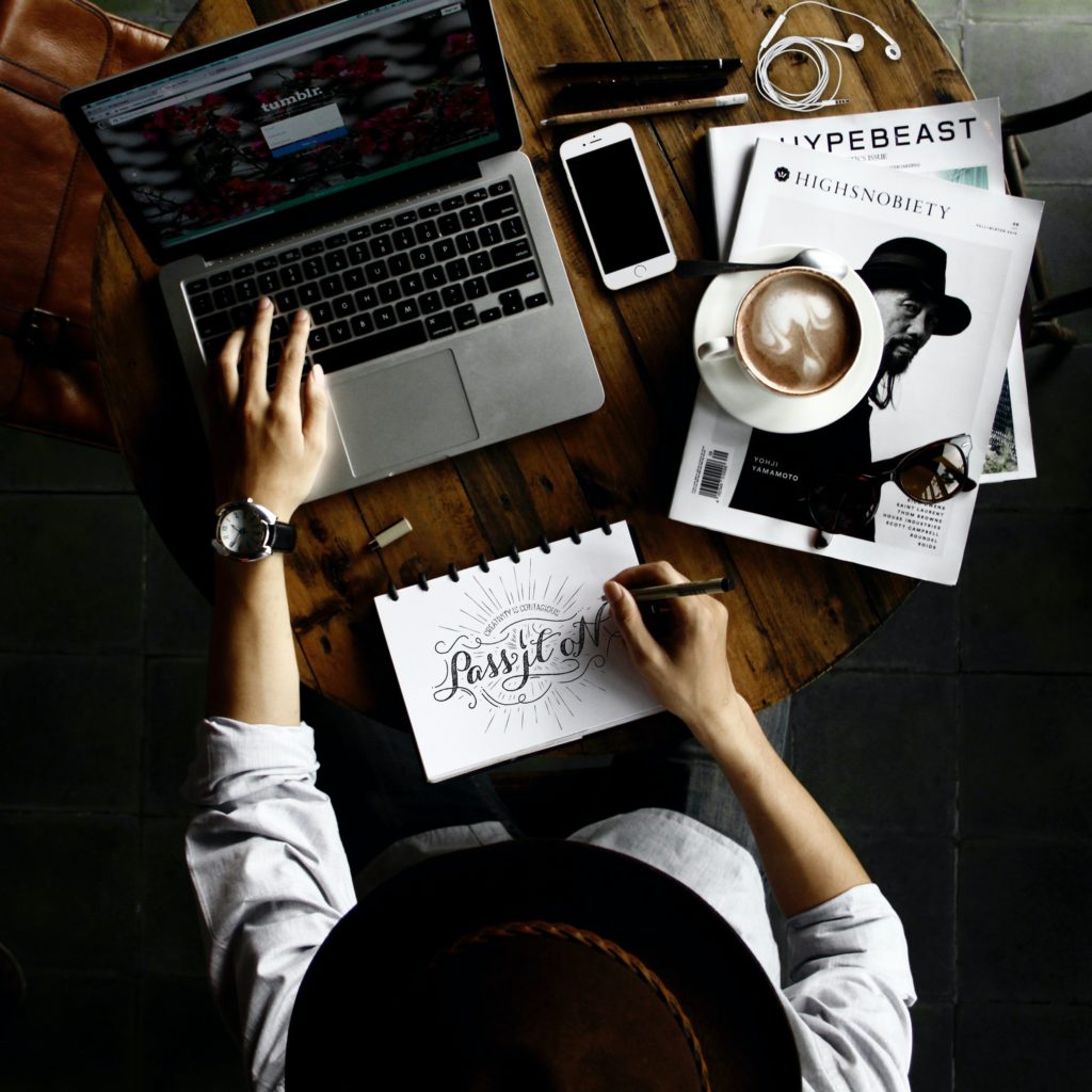 woman in hat using laptop with coffee