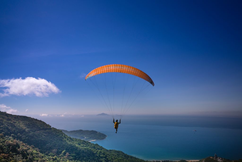 A man paragliding over verdant cliffs