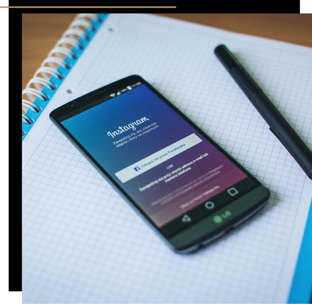 A phone resting on a notebook next to a pen with the Instagram login page open
