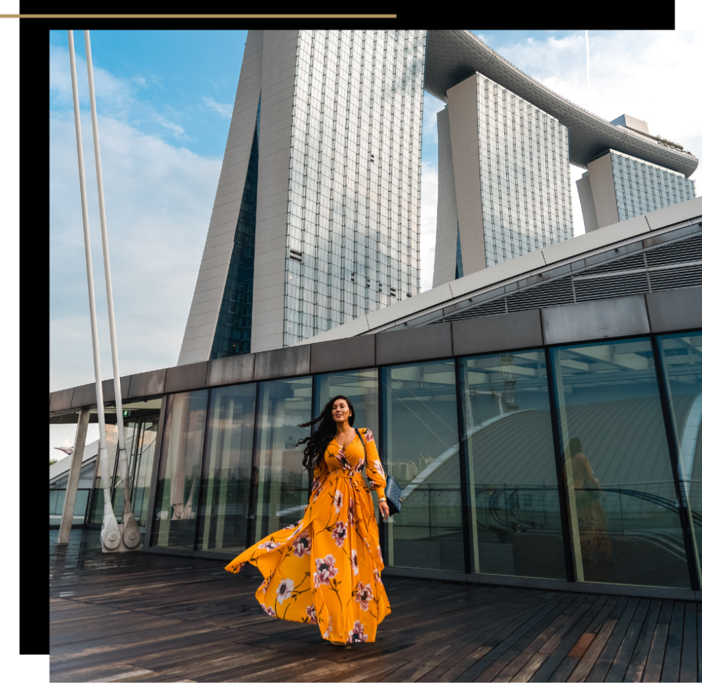 Isabella standing in front of Marina Bay Sands skyscraper in Singapore, wearing a floral orange dress