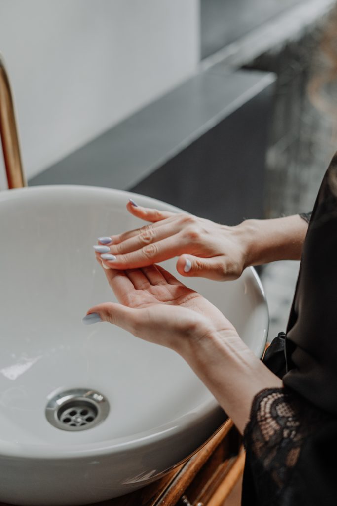 Woman working moisturizer between her hands at the sink 
