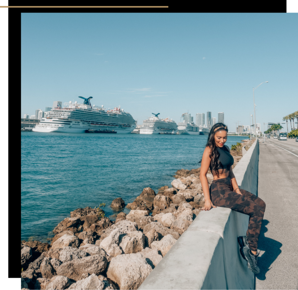 Isabella in activewear sitting on a wall with cruises in the background in Miami