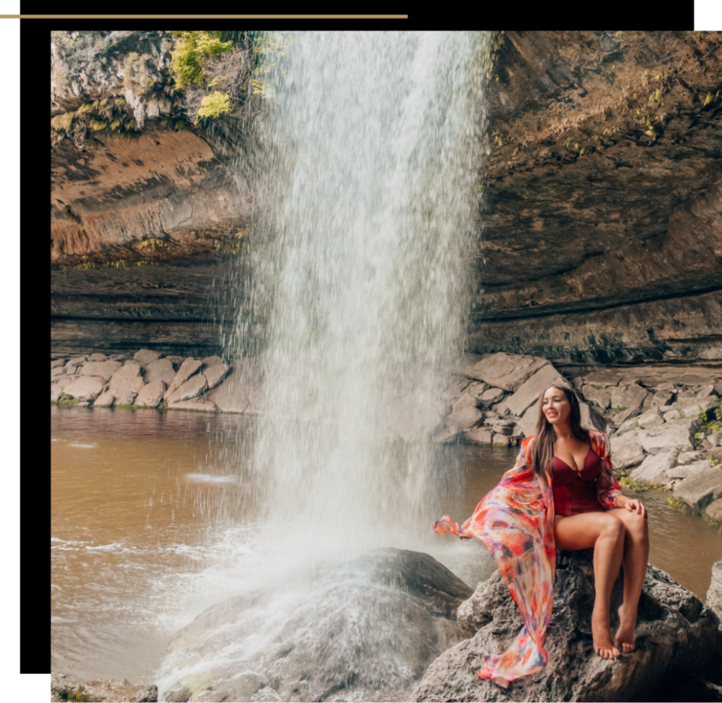 Isabella in a red swimsuit sitting on the rocks of the Hamilton Pool in Austin, Texas