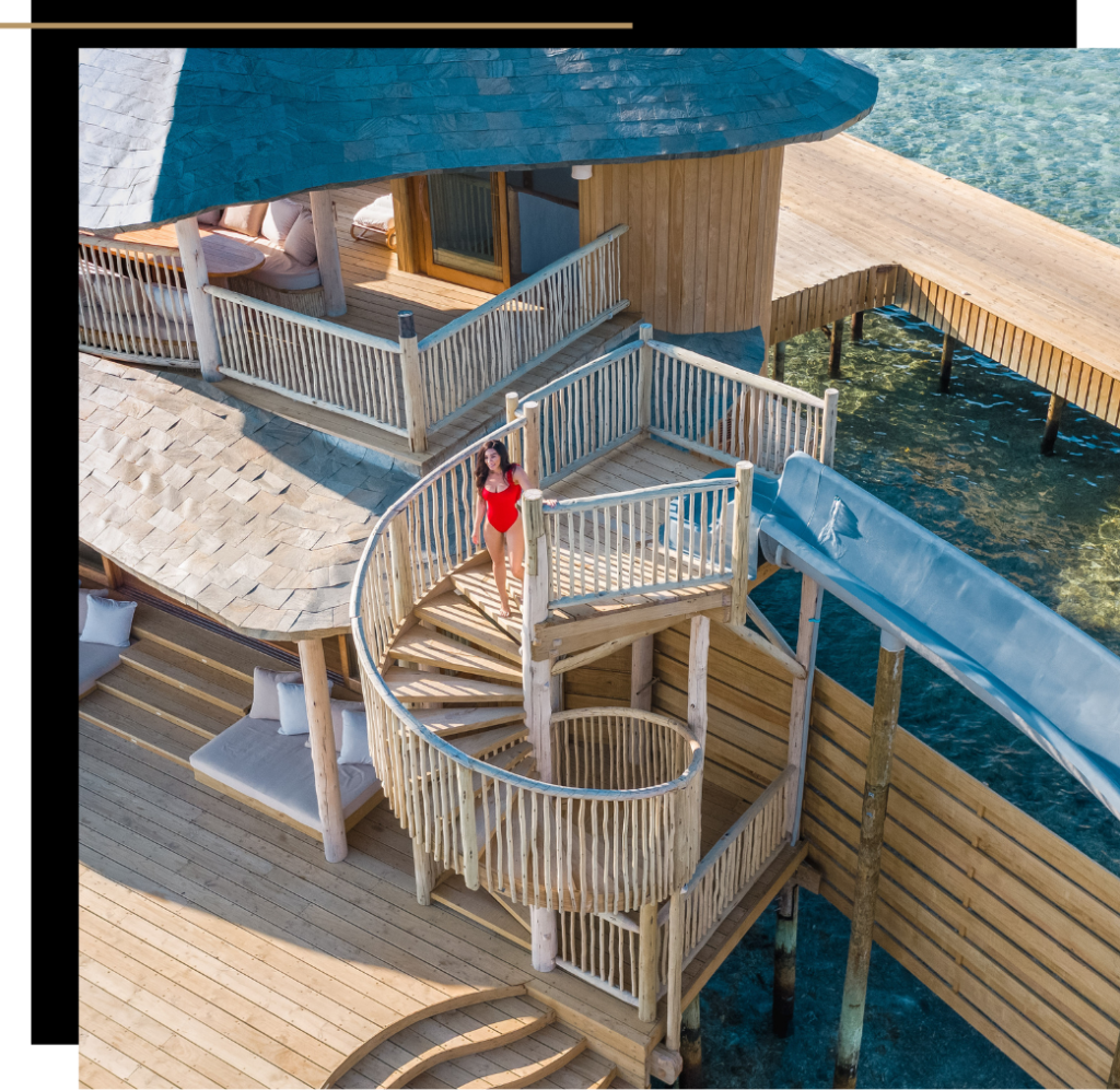 Isabella in a red swimsuit at the top of the spiral staircase in a Soneva Fushi overwater villa in The Maldives