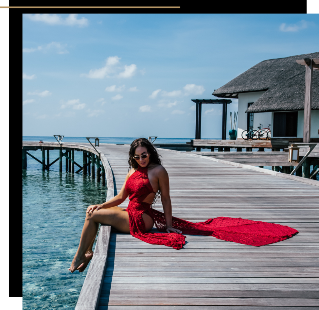 Isabella in a red dress sitting on the pier at Jumeirah Maldives